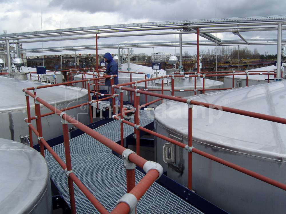 Interclamp tube clamp fittings used to assemble a protective safety guardrail along a walkway at a chemical plant, ensuring worker safety in a high-risk area.